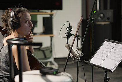 violoncelliste devant sa partition enregistrée en studio acoustique